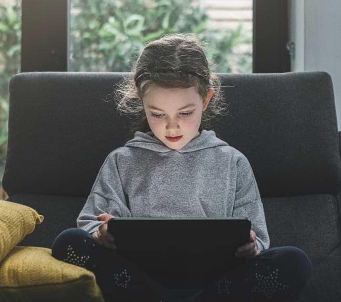 Dívka na pohovce s notebookem se spuštěnou aplikací Norton Family.