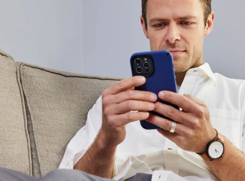 Muž na pohovce koukající do telefonu