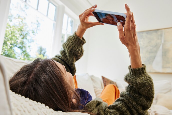 Ležící žena dívající se na mobilní telefon